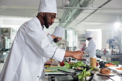 Preview: Food industry expert adding fresh green herbs to improve dish taste.