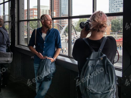 Preview: Woman photographing man standing by window