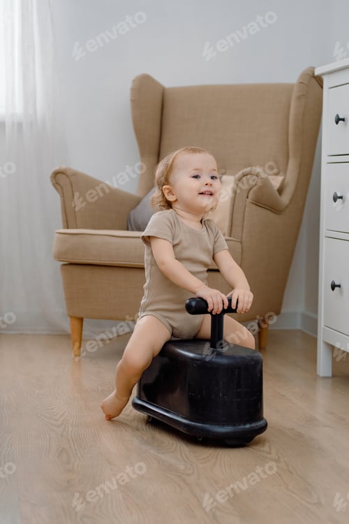Preview: A cute smiling toddler riding kids push car at modern home interior of bedroom.