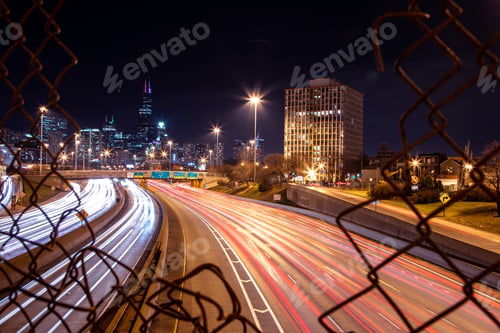 Preview: Long exposure shot of the cars on a highway captured through the fences at night in Chicago, USA