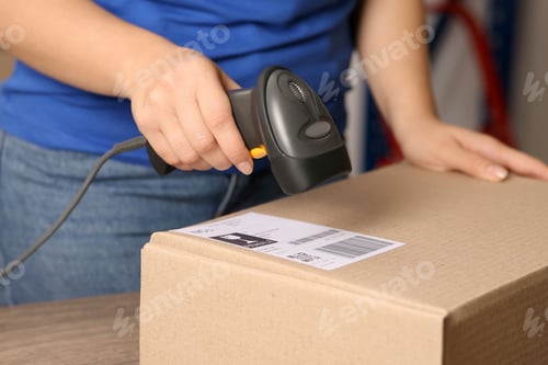 Preview: Post office worker with scanner reading parcel barcode at counter, closeup