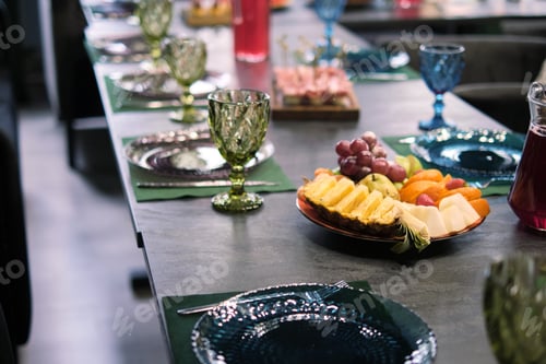 Preview: Sophisticated table arrangement, green glassware in focus, with a spread of tropical fruits
