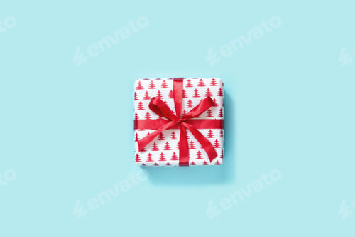 Preview: Christmas gift with red ribbon on blue background. View from above.