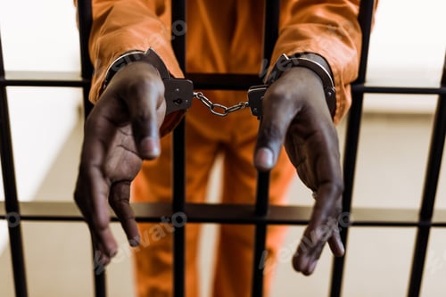 Preview: cropped image of african american prisoner in handcuffs behind prison bars