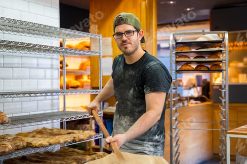 Preview: Portrait of baker of bakery in the workshop workshop of artisan bakery with the shovel of bread