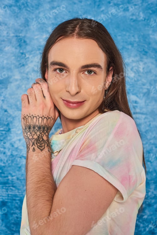 Preview: Portrait of young long haired and tattooed gay man looking at camera during lgbt community