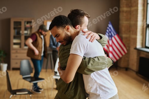 Preview: Young man giving hug to his friend with post traumatic syndrome