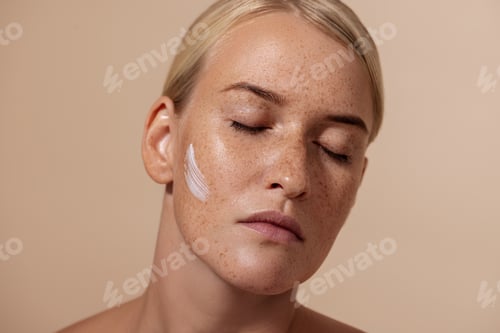 Preview: Close up portrait of beautiful caucasian woman with anti aging cream on face