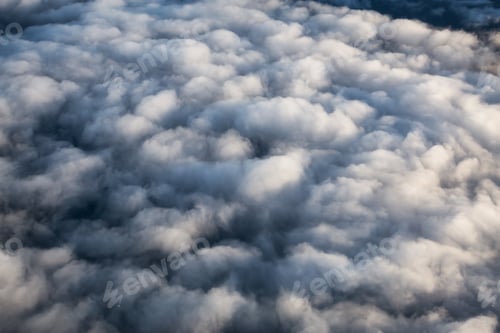 Preview: Aerial view from above a white and puffy clouds during a sunny sunrise