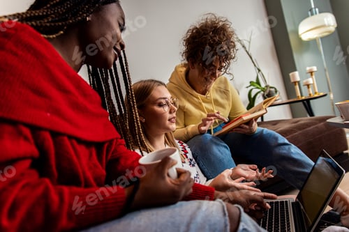 Preview: Diverse group female students learning at home using laptop and books for research.