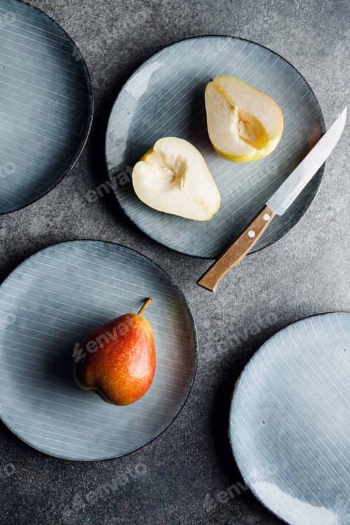 Preview: Blue food ceramic set with plates and pears over grey textured background.
