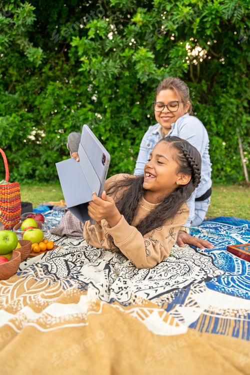 Preview: Mother and daughter enjoying video call during picnic