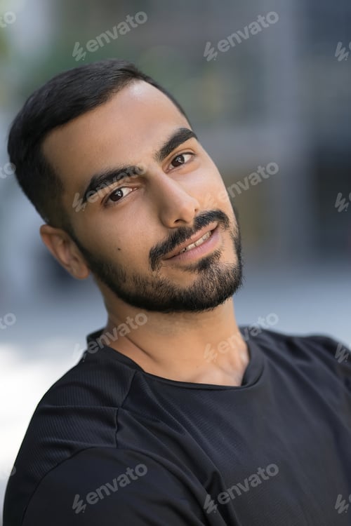 Preview: Smiling confident middle eastern man looking at camera on the street