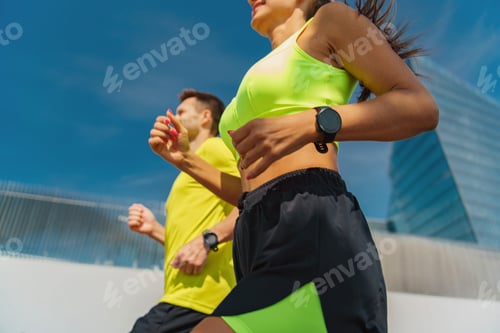 Preview: Two joggers in bright athletic wear running, focused on their workout, Fitness watch runners use the