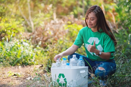 Preview: A woman making thumbs up hand sign while collecting garbage plastic bottles into a recycle bin