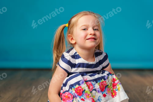 Preview: Funny little toddler girl smiling against blue background