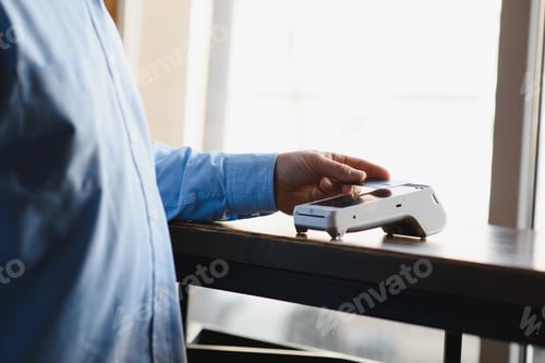 Preview: Mature businessman paying with contactless credit card with NFC technology.