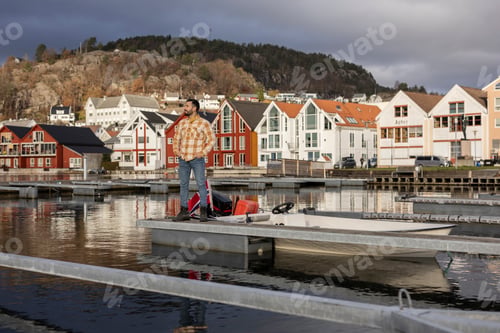 Preview: Man with Gear Standing by Boat in Scenic Norwegian Town