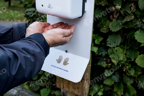 Preview: Close up of person using automatic hand sanitizer dispenser during Corona virus crisis.