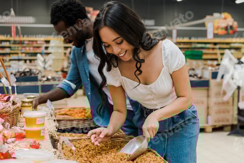 Preview: selective focus of happy asian woman looking at dried apricots near cheerful african american man in