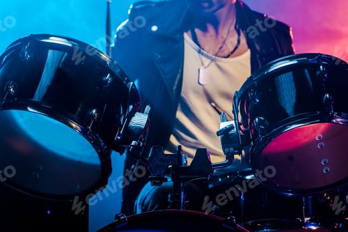 Preview: cropped shot of male musician playing drums during rock concert on stage with smoke and dramatic