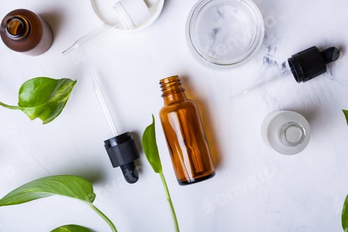 Preview: Glass bottles and jar for natural cosmetics on a white marble background