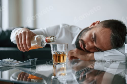 Preview: Conception of addiction. Upset young man drinker alcoholic is indoors