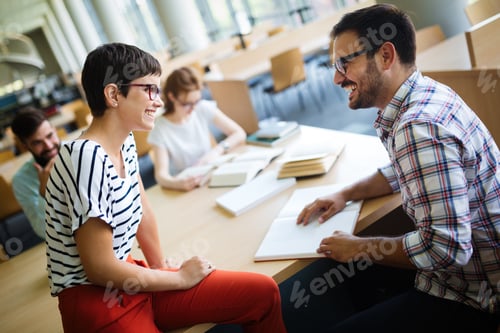Preview: Happy young university students studying with books in library