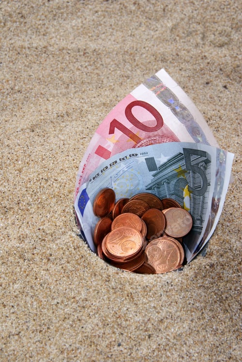 Preview: Close-up shot of euro bill paper envelope on the sand with euro coins inside, budgeting concept