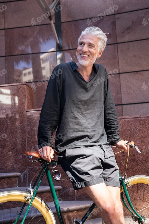 Preview: Mature man in the city leaning on his bicycle