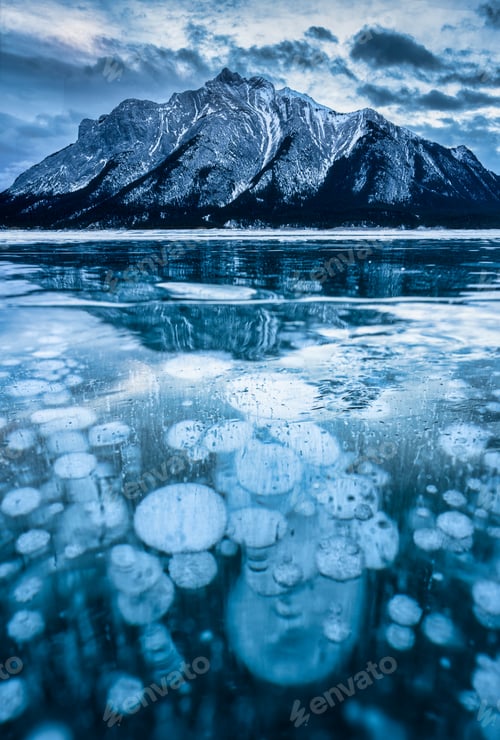 Preview: Frozen Abraham Lake with rocky mountains and natural bubbles frost on winter