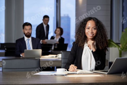 Preview: Smiling ethnic businesswoman at table in office