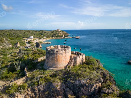 Preview: Aerial shot of a castle at Fort Beekenburg near Tugboat beach with blue seawater and skyscape