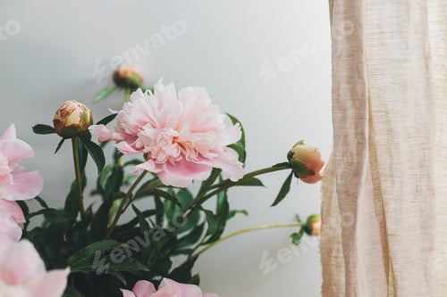 Preview: Beautiful peonies bouquet in basket in boho room, moody image. Modern bohemian decor