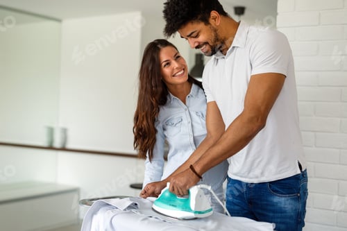 Vista previa: Young couple at home doing hosehold chores and ironing