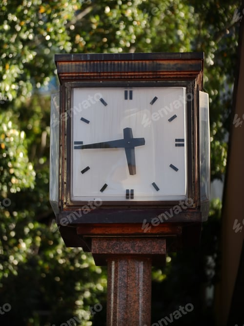 Preview: Clock situated on a city street with trees in the background