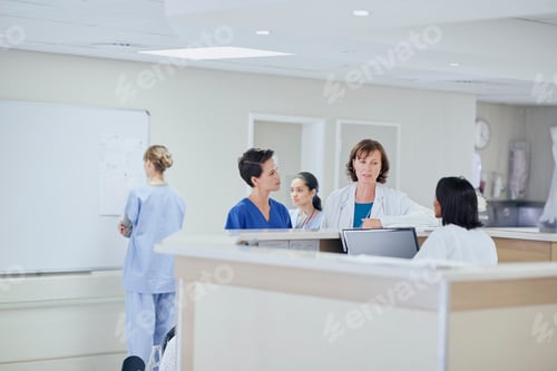 Preview: Female doctor having discussion with nurses at nurses station in hospital