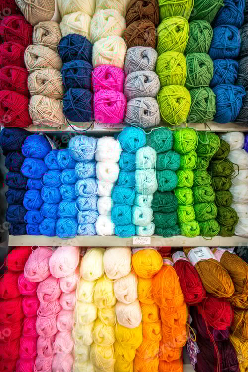 Preview: Balls of wool or yarn in a store for sale displayed in rows and various colours on wooden shelves.