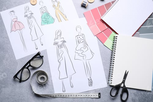 Preview: Sketches of stylish clothes and other fashion designer`s supplies on grey table, flat lay