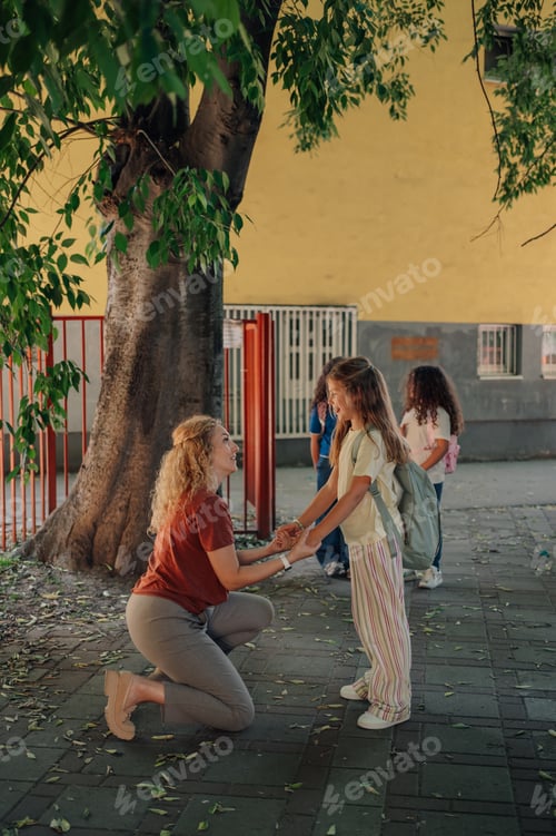 Preview: Teacher kneeling and holding student's hands at school