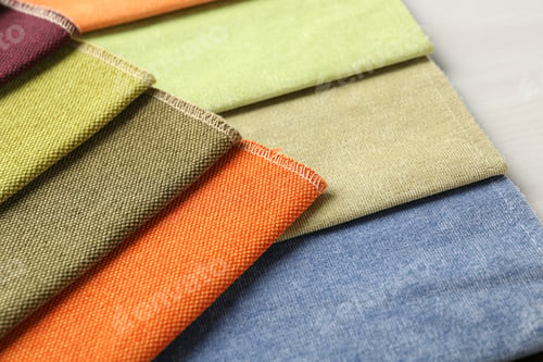 Preview: Samples of different fabrics on light wooden table, closeup