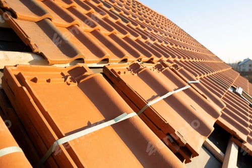 Preview: Stacks of yellow ceramic roofing tiles for covering residential building roof under construction.