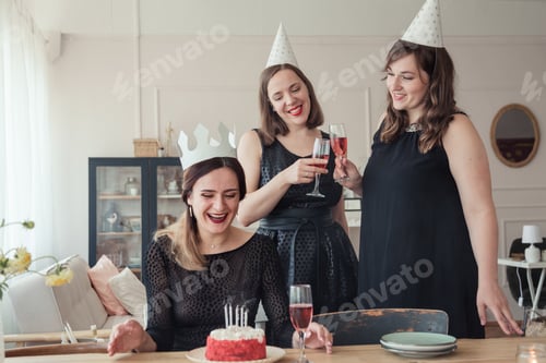 Preview: Women with wine glasses celebrate birthday. The birthday girl blows out the candles on the cake.