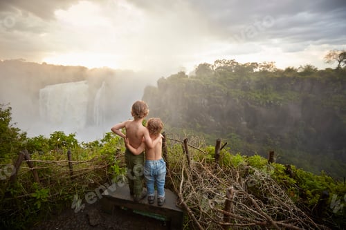 Preview: Two young boys standing on ledge admiring the view, rear view, Victoria Falls, Livingstone, Zimbabwe
