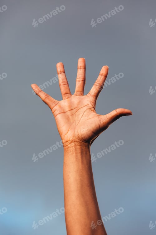 Preview: Hand of black woman against a blue sky