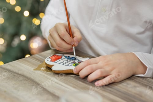 Preview: Little boy draws food paints on Christmas homemade gingerbread cookies. Christmas concept. Close up
