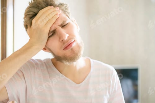 Preview: close up portrait of young bearded person suffering from strong headache f
