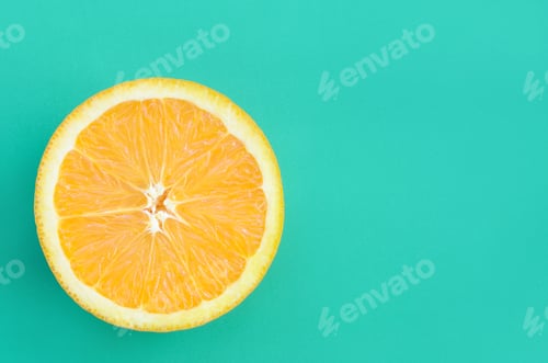 Preview: Top view of a one orange fruit slice on bright background in turquoise green color
