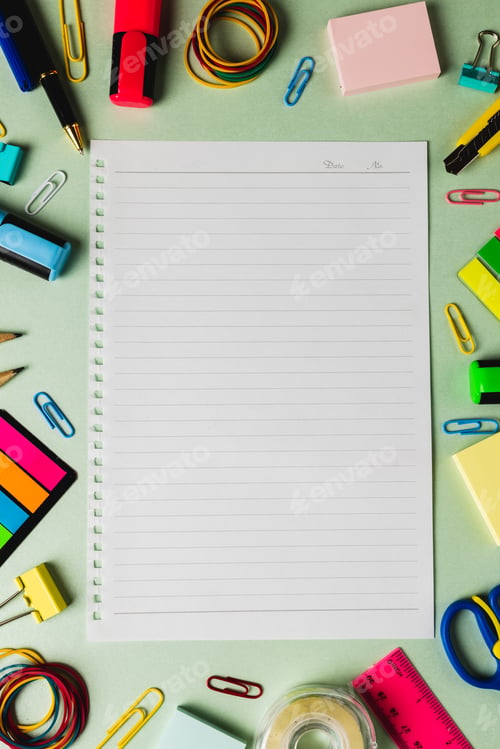 Preview: Vertical composition of notebook with copy space and frame of school tools on green surface