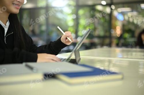 Preview: Close-up view of young female student working on digital tablet for homework or virtual class